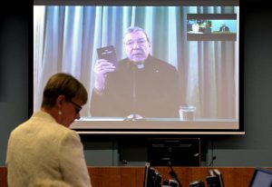 Senior Counsel Assisting Gail Furness stands in front of a screen displaying Australian Cardinal George Pell as he holds a bible while appearing via video link from a hotel in Rome, Italy to testify at the Australia's Royal Commission into Institutional Response to Child Sexual Abuse in Sydney, Australia, February 29, 2016. Australian Cardinal George Pell said on Sunday the Catholic Church had made "enormous mistakes" as he became the highest-ranking Vatican official to testify on sexual abuse of children in the Church. Pell, 74, held up a Bible as he was sworn in to answer questions by Australia's Royal Commission into Institutional Response to Child Sexual Abuse in front of victims in a Rome hotel room. REUTERS/Jeremy Piper-Oculi/Handout via Reuters ATTENTION EDITORS - THIS PICTURE WAS PROVIDED BY A THIRD PARTY. REUTERS IS UNABLE TO INDEPENDENTLY VERIFY THE AUTHENTICITY, CONTENT, LOCATION OR DATE OF THIS IMAGE. IT IS DISTRIBUTED EXACTLY AS RECEIVED BY REUTERS, AS A SERVICE TO CLIENTS. FOR EDITORIAL USE ONLY. NOT FOR SALE FOR MARKETING OR ADVERTISING CAMPAIGNS. NO RESALES. NO ARCHIVE. TPX IMAGES OF THE DAY